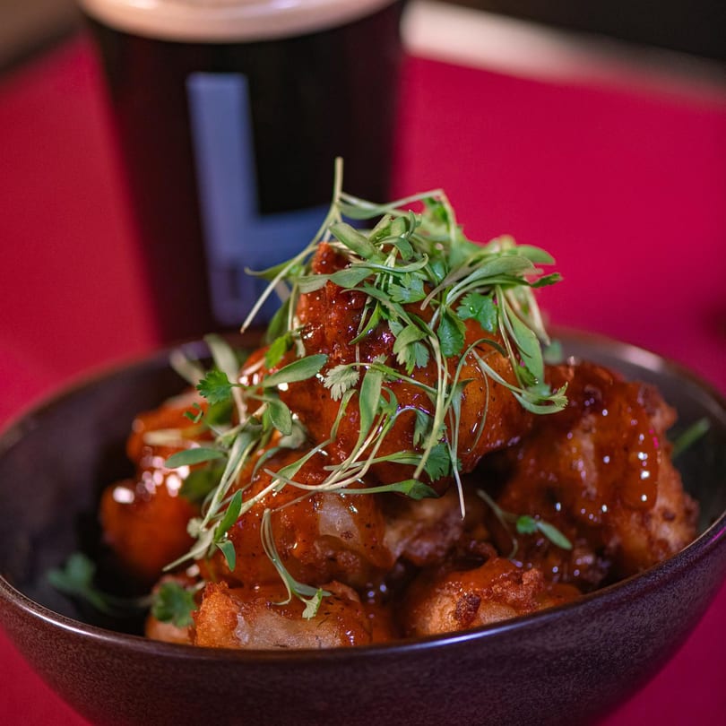 Legion Sports Bar's Southern-style boneless wings, coated in a rich, glossy sauce and garnished with fresh herbs.
