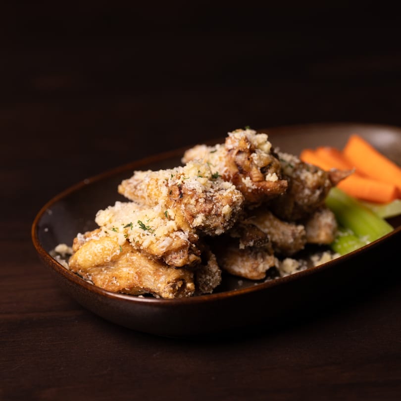 Legion Sports Bar's crispy southern-style wings, topped with parmesan and herbs, served with carrots and celery.
