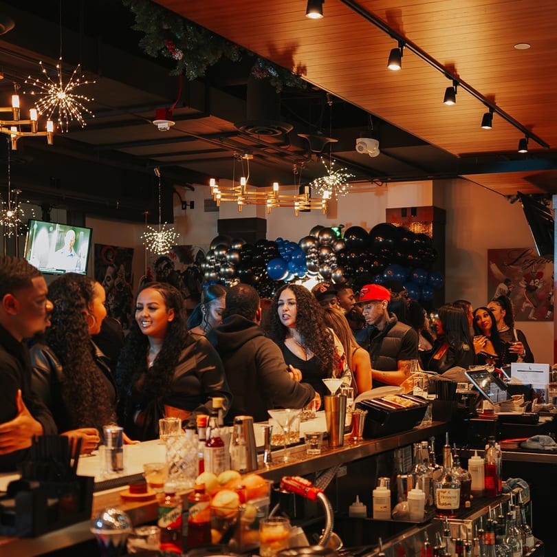 Patrons socialize at a lively bar with drinks, balloons, and decorative lighting at Legion Sports Bar.