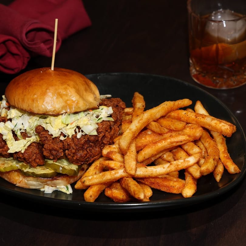 Legion Sports Bar's Southern fried chicken sandwich with coleslaw, pickles, and a side of fries.