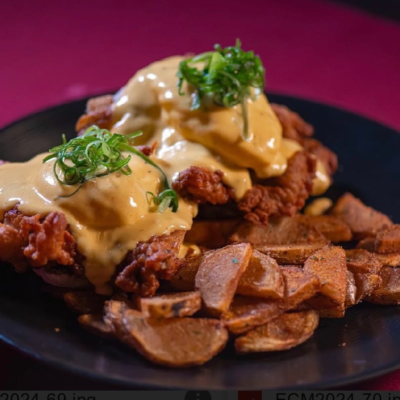 Southern fried chicken and potato wedges topped with creamy sauce and green onions.